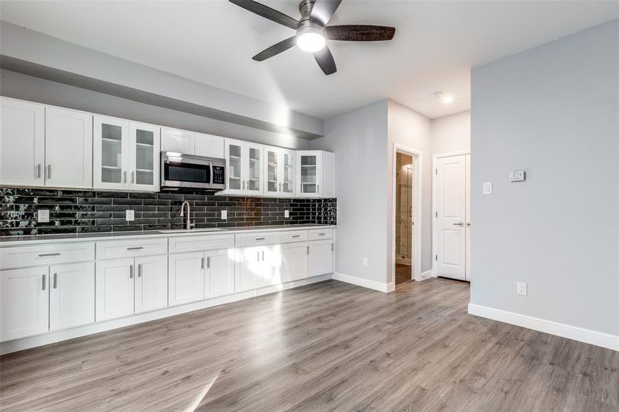 Kitchen with sink, white cabinetry, light hardwood / wood-style flooring, ceiling fan, and decorative backsplash