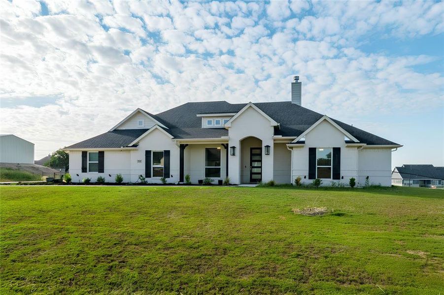 Modern farmhouse featuring a front yard, a chimney, and a shingled roof