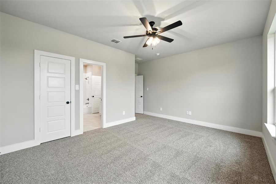 Unfurnished bedroom with light colored carpet, ensuite bathroom, and ceiling fan Unfurnished bedroom with light colored carpet, ensuite bathroom, and ceiling fan