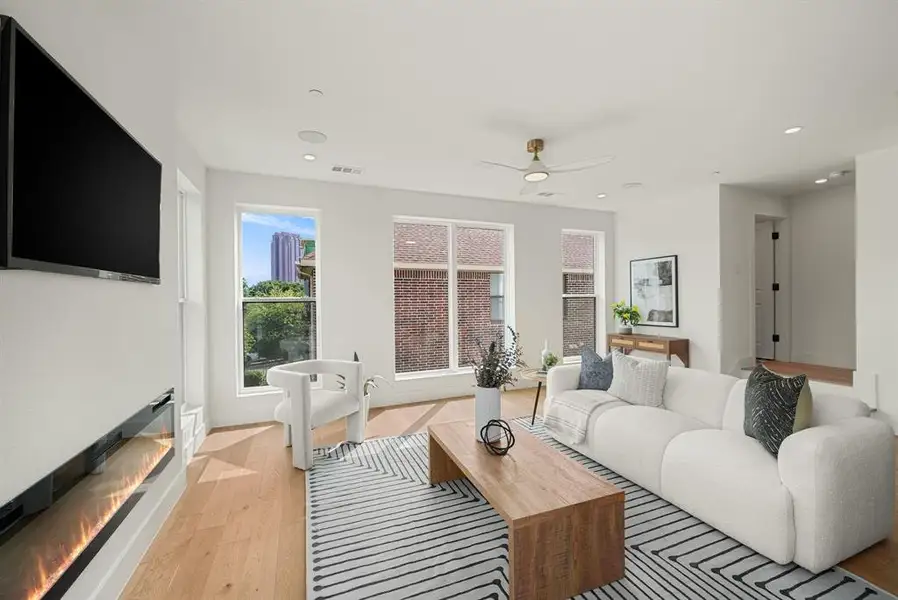 Spacious living area featuring light wood-finish flooring, recessed lighting, and large windows Spacious living area featuring light wood-finish flooring, recessed lighting, and large windows