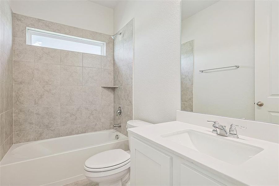 Full bathroom with toilet, tiled shower / bath, and vanity