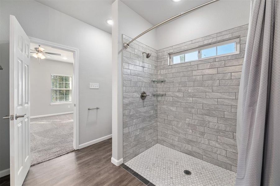 Bathroom with curtained shower, hardwood / wood-style floors, and ceiling fan