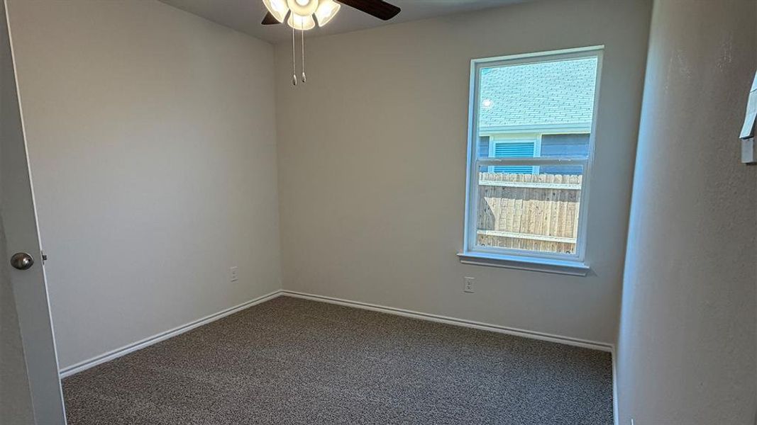 Spare room with ceiling fan and dark colored carpet