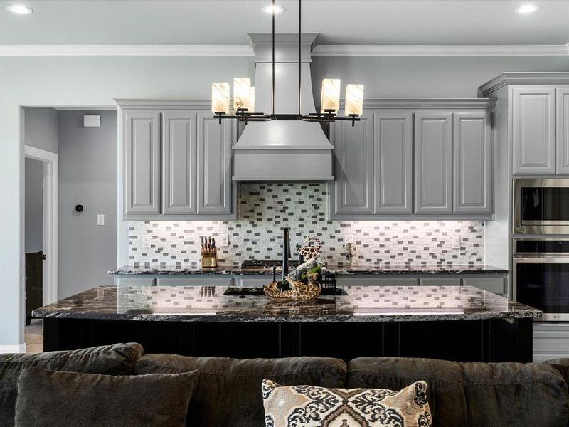 Kitchen featuring open floor plan, dark stone counters, crown molding, backsplash, and recessed lighting Kitchen featuring open floor plan, dark stone counters, crown molding, backsplash, and recessed lighting