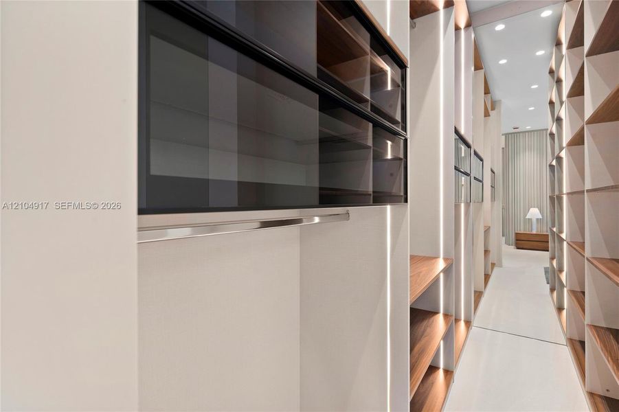 Built-in custom cabinetry with wood-finish shelving, recessed lighting, and integrated hanging rods