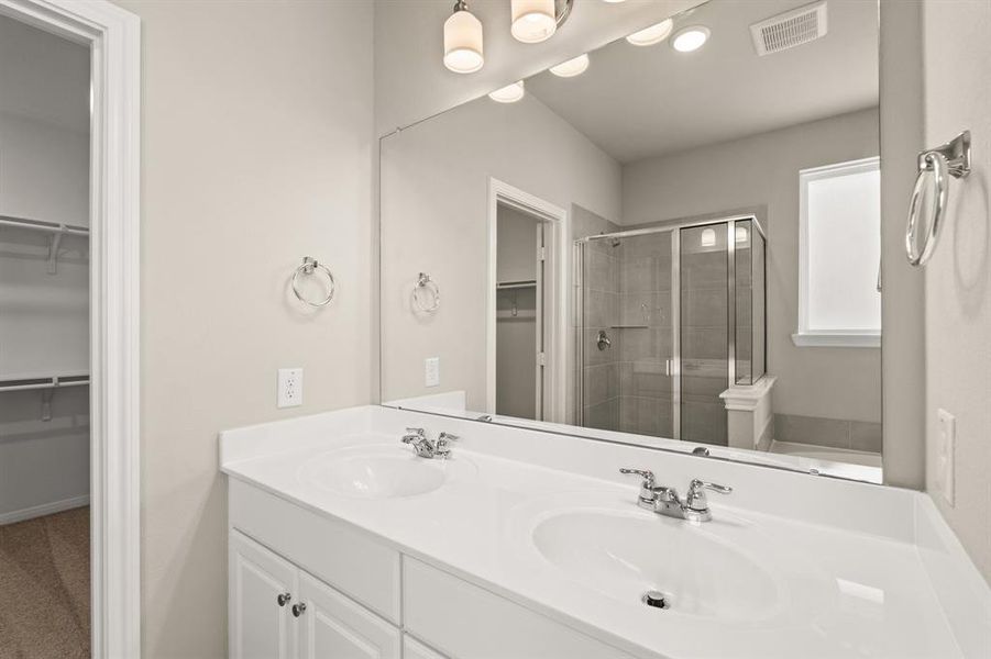 The en-suite bathroom offers a spa-like atmosphere with its elegant design, high end finishes, and tasteful lighting, creating a retreat within your own home.