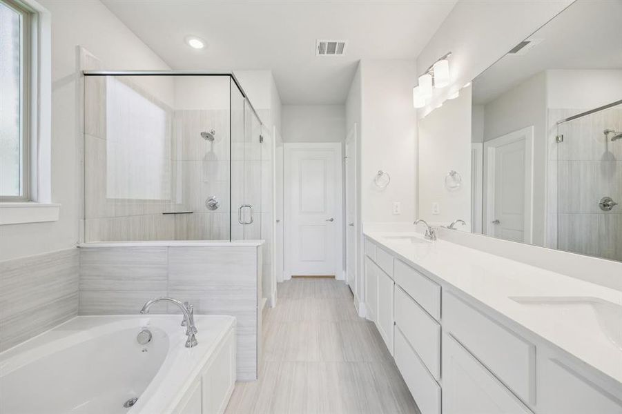 Full bath featuring double vanity, a garden tub, and a stall shower