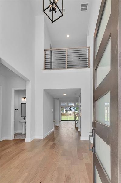 Entryway with an inviting chandelier, light hardwood / wood-style flooring, and a high ceiling