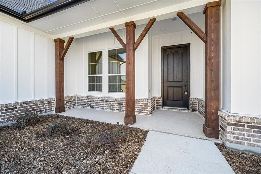 View of exterior entry featuring board and batten siding and covered porch