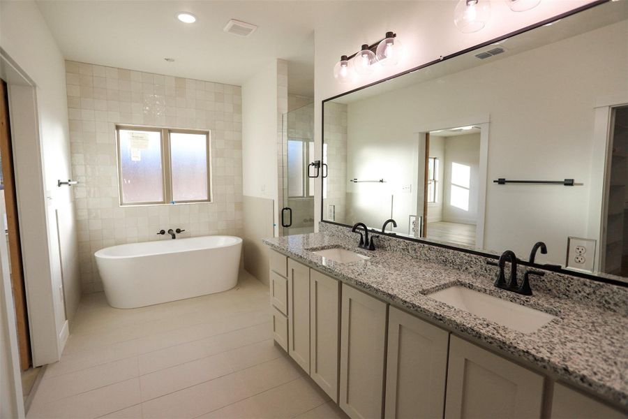Bathroom with double vanity, light tile patterned flooring, a soaking tub, tile walls, and recessed lighting