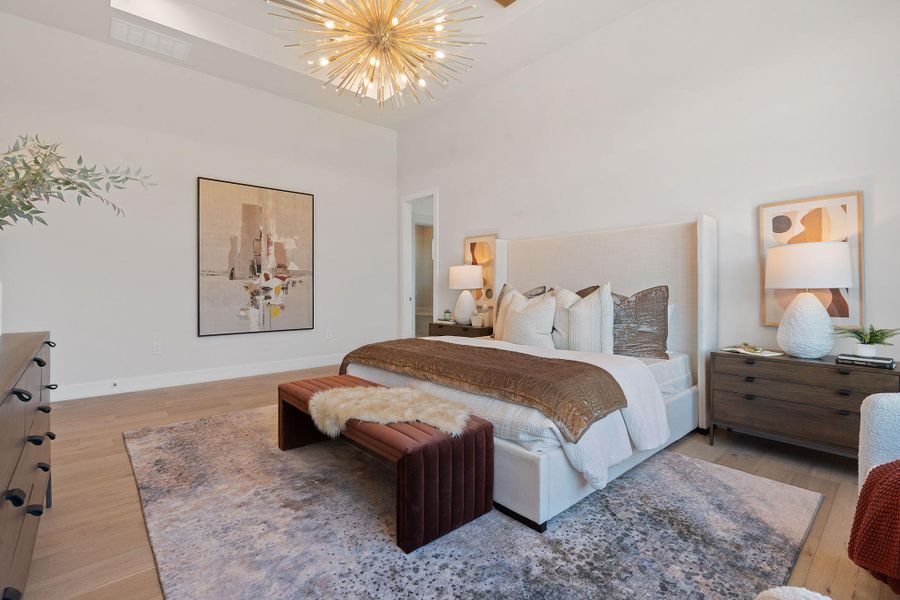 Bedroom featuring a high ceiling, and inviting chandelier, baseboards, light natural wood flooring Bedroom featuring a high ceiling, and inviting chandelier, baseboards, light natural wood flooring