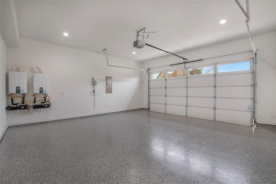 Garage featuring electric panel, tankless water heater, and a garage door opener