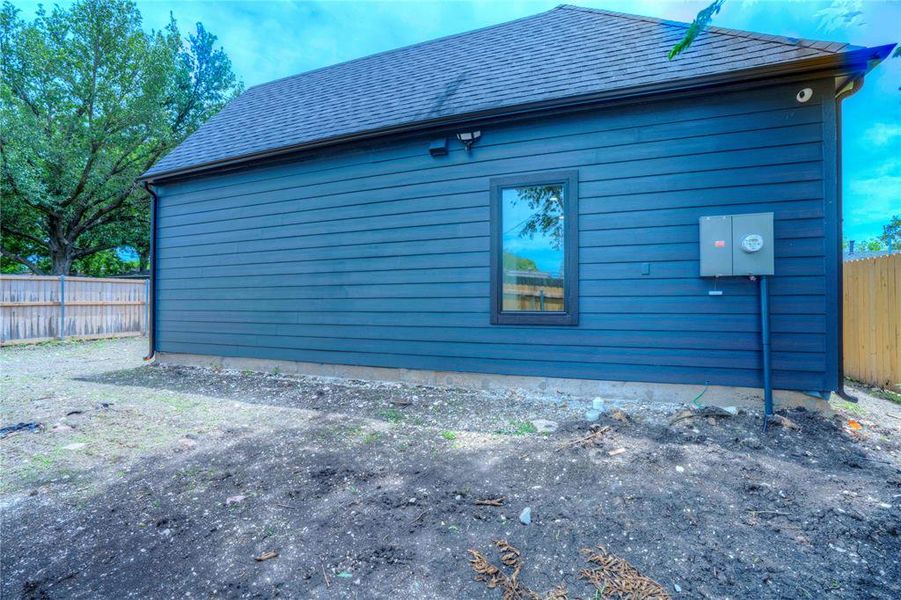 Exterior featuring horizontal siding, a single window with dark trim, a dark shingled roof, and dark gutters