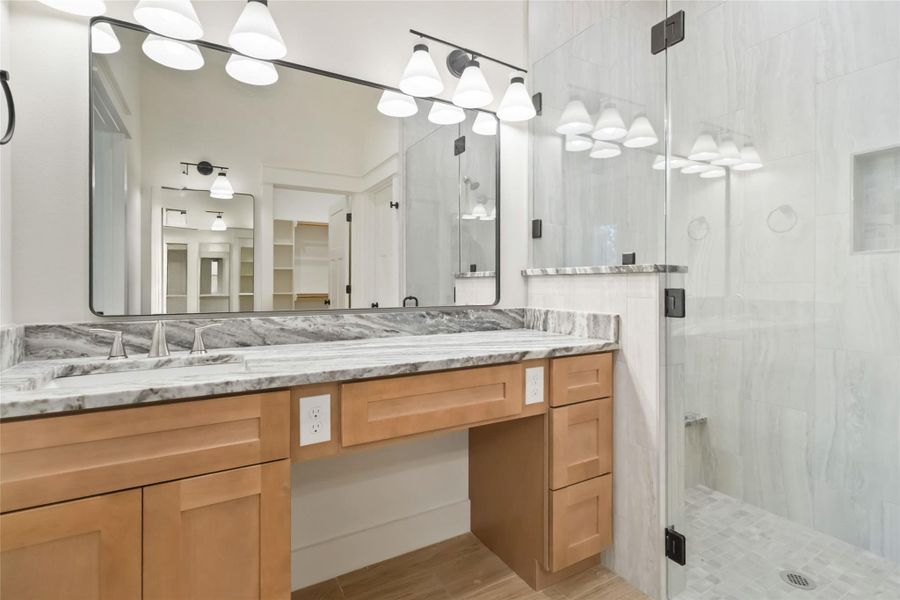 Primary ensuite on the main level with separate vanities and a frameless glass walk-in shower with bench seat. Primary ensuite on the main level with separate vanities and a frameless glass walk-in shower with bench seat.