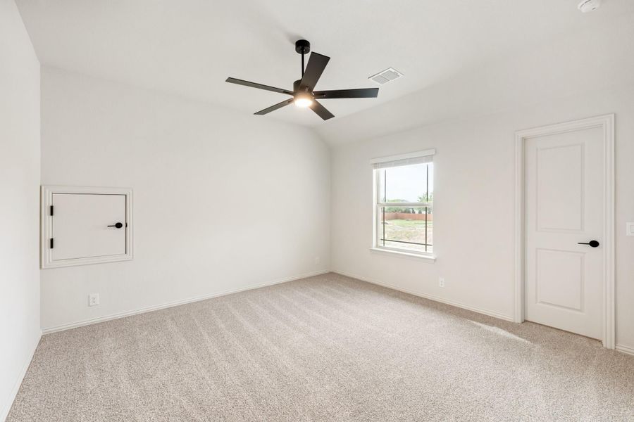 Empty bedroom with carpet flooring, black ceiling fan, vaulted ceiling, and a single window Empty bedroom with carpet flooring, black ceiling fan, vaulted ceiling, and a single window