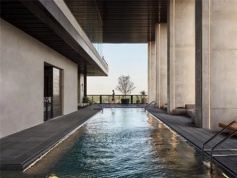 Dramatic structural columns frame a sleek swimming pool set beneath a high covered terrace. Dramatic structural columns frame a sleek swimming pool set beneath a high covered terrace.