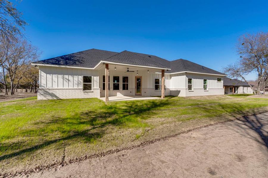 Rear view of house featuring ceiling fan, a patio area, and a yard