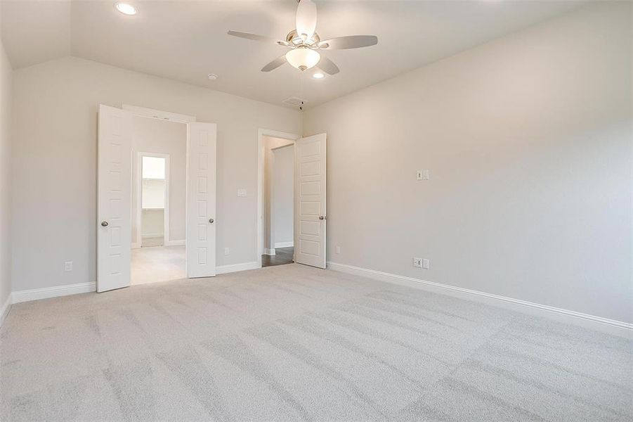 Unfurnished bedroom with ceiling fan, vaulted ceiling, and light colored carpet