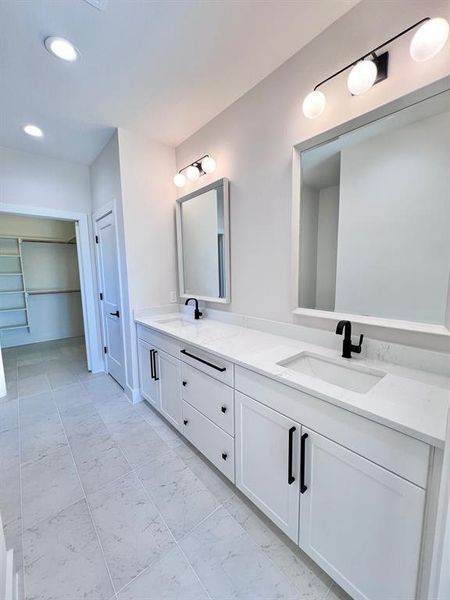 Master Bathroom with decorative tile, light fixtures, white cabinets and matte black pulls. Dual Vanities, Framed Mirrors and a walk in shower