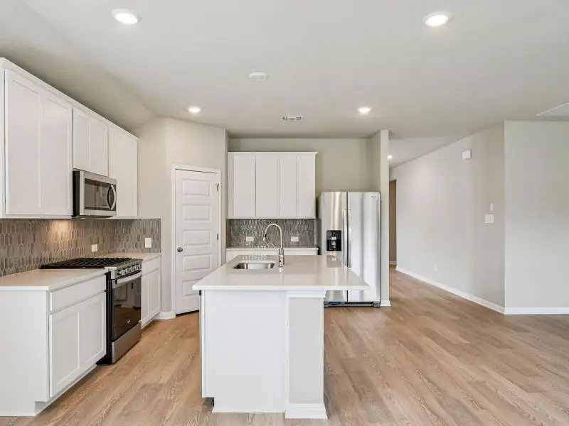 Kitchen with appliances with stainless steel finishes, backsplash, recessed lighting, a center island with sink, and light countertops Kitchen with appliances with stainless steel finishes, backsplash, recessed lighting, a center island with sink, and light countertops