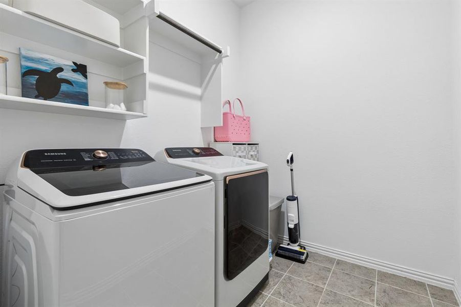 Dedicated laundry space with built-in shelving, hanging rod, and neutral tile flooring