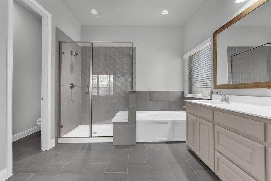 Full bathroom with vanity, a bath, a stall shower, dark tile patterned flooring, and recessed lighting
