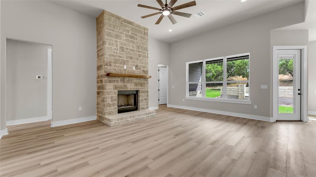 Unfurnished living room featuring ceiling fan, a stone fireplace, light wood-style flooring, and recessed lighting