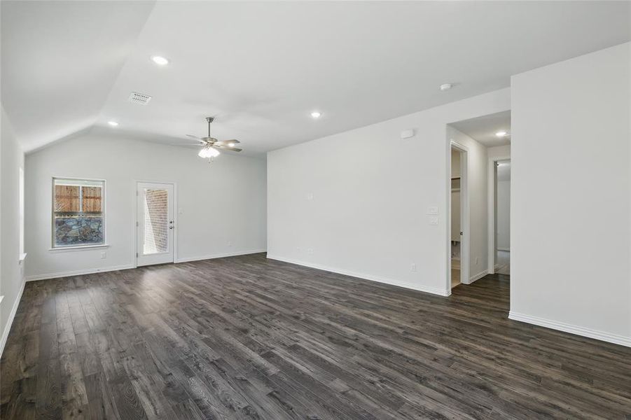 Unfurnished living room featuring lofted ceiling, dark wood finished floors, and visible vents