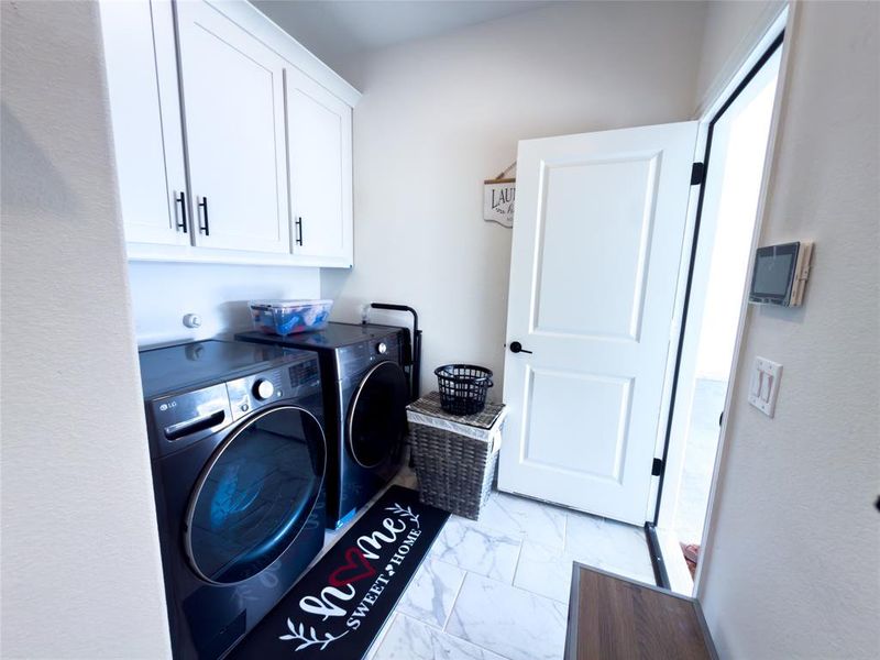 Laundry area with cabinet space, light marble finish flooring, and washing machine and clothes dryer
