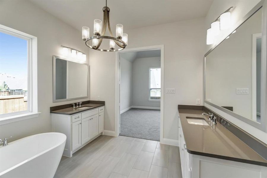 Bathroom featuring tile patterned flooring, a bathing tub, a chandelier, and dual bowl vanity