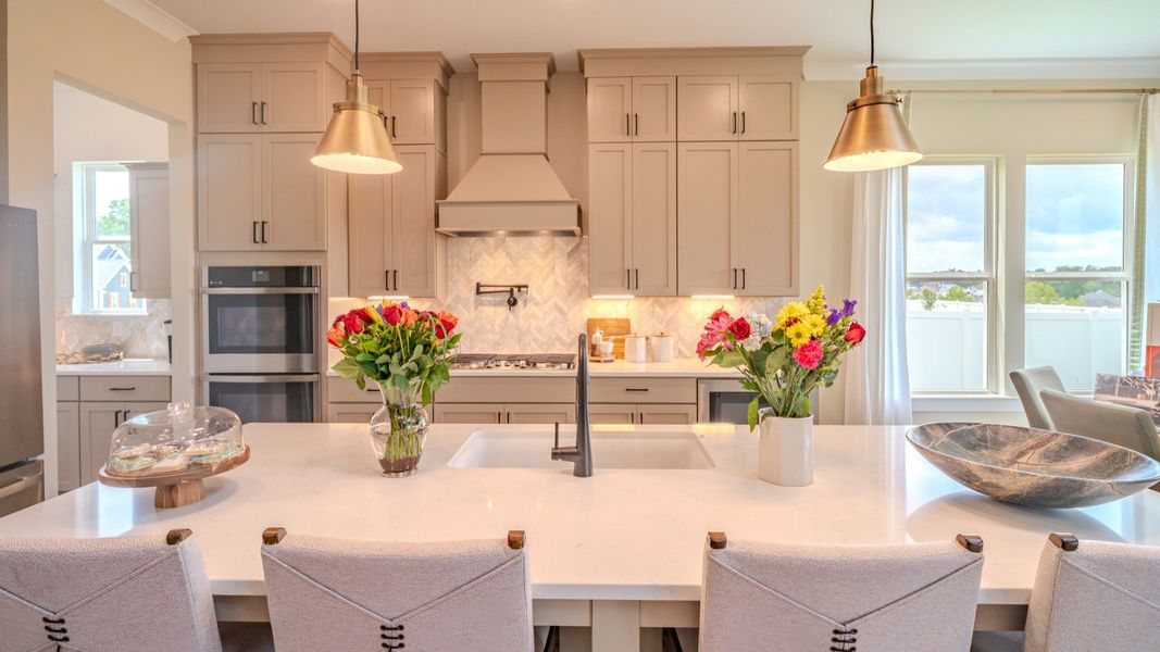 Kitchen with tile backsplash, quartz countertops, and pendant lighting Kitchen with tile backsplash, quartz countertops, and pendant lighting