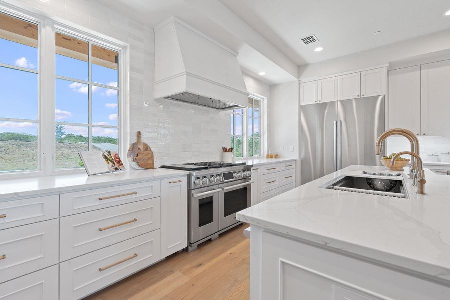 Kitchen with a sink, stainless steel appliances, decorative backsplash, a wealth of natural light, and custom exhaust hood Kitchen with a sink, stainless steel appliances, decorative backsplash, a wealth of natural light, and custom exhaust hood