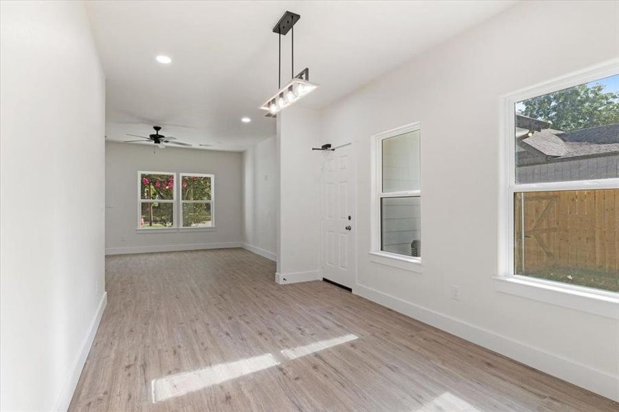 Spare room with a healthy amount of sunlight, ceiling fan, and light hardwood / wood-style flooring