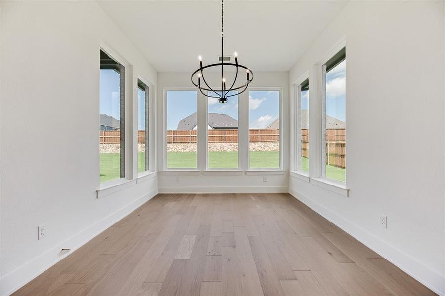 Unfurnished sunroom featuring wood finished floors and a chandelier