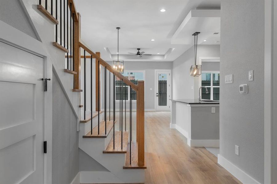 Staircase featuring recessed lighting, baseboards, wood finished floors, and ceiling fan with notable chandelier