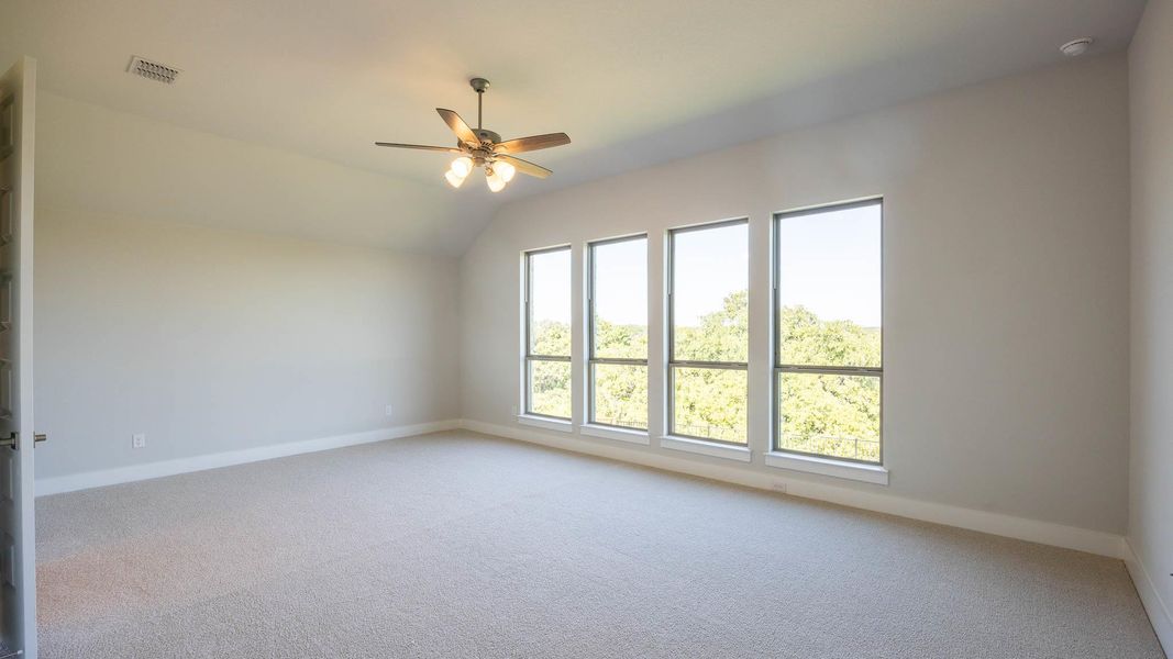 Empty room featuring light colored carpet, ceiling fan, and lofted ceiling