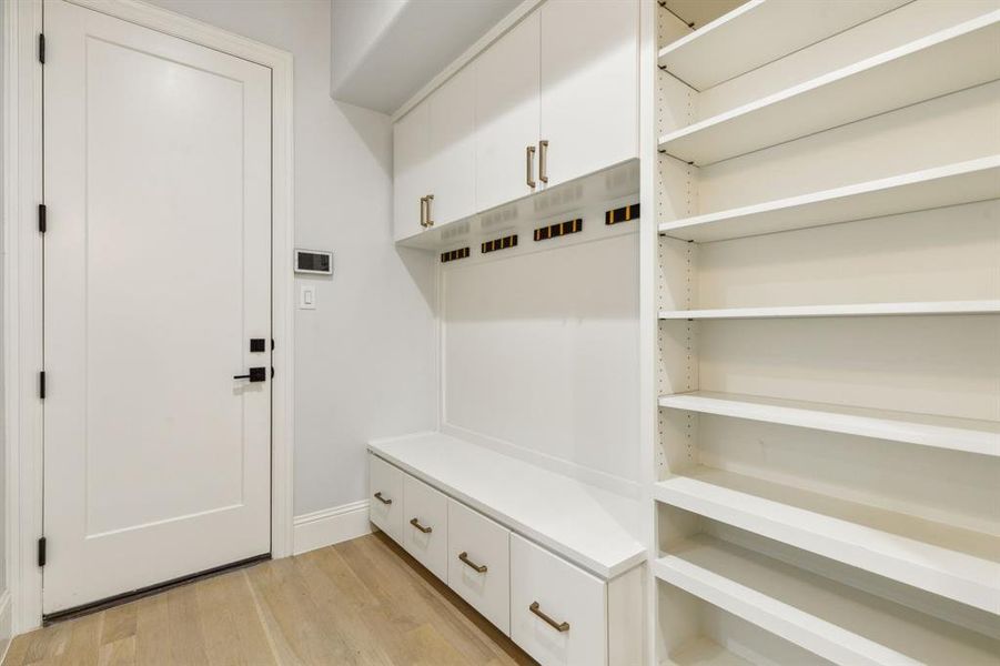 Mud room with upper and lower cabinets, flip-down hooks and ample shelving for shoes