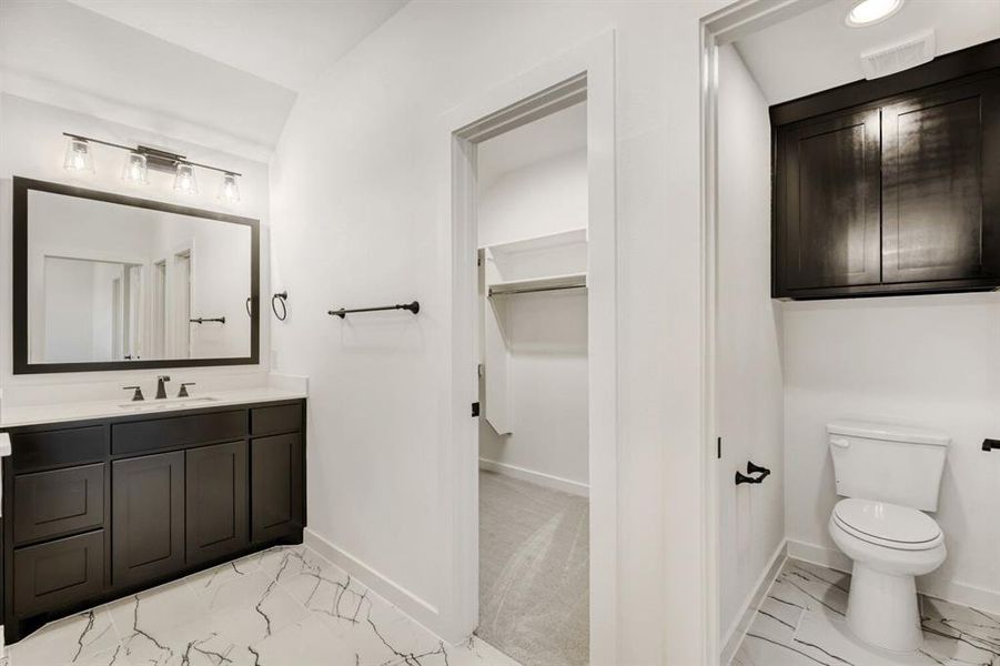 Bathroom with light marble finish floors, vanity, and a walk in closet