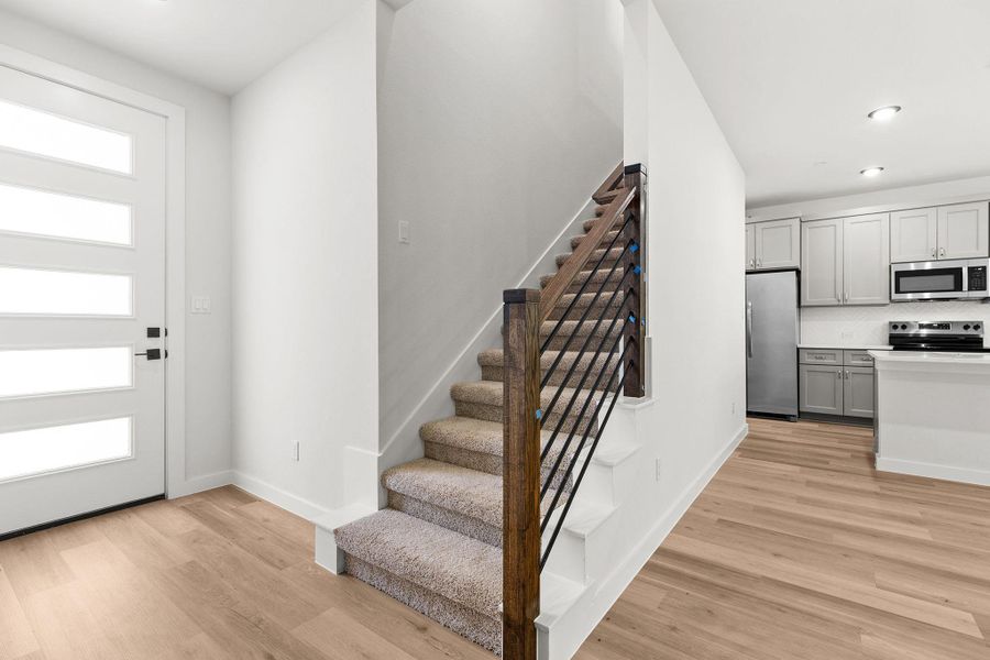 Seamlessly blending style and function, a modern staircase and light-toned hardwood flooring flow into an efficient kitchen. Seamlessly blending style and function, a modern staircase and light-toned hardwood flooring flow into an efficient kitchen.