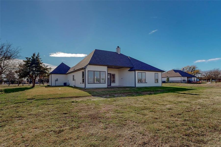 Back of property featuring central AC and a lawn