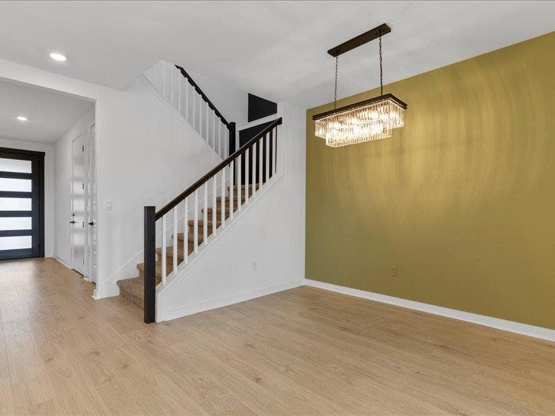Foyer featuring light wood-style flooring, stairs, and a chandelier