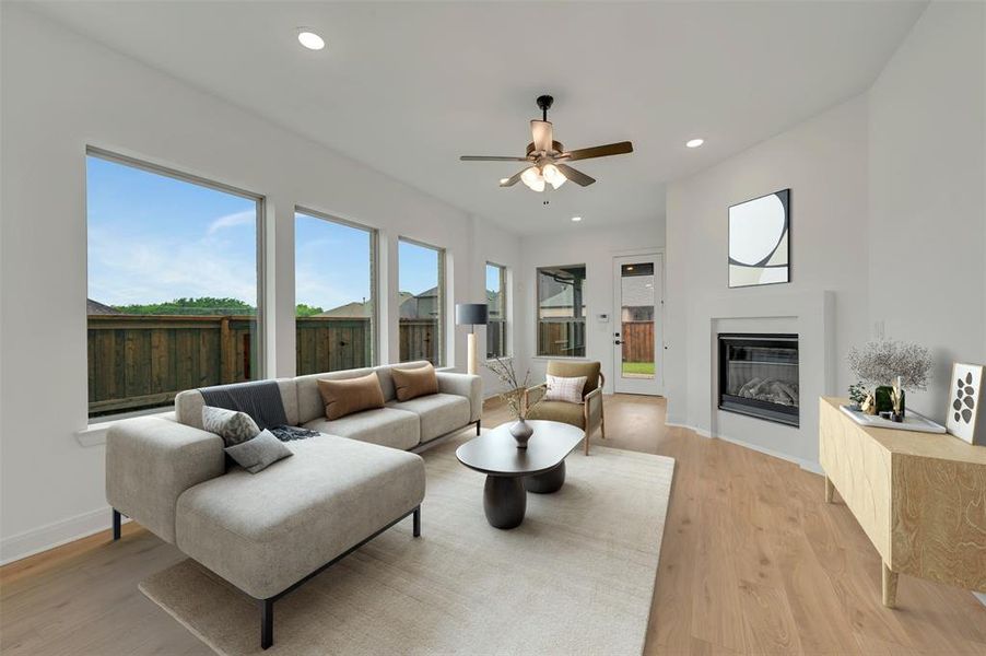 Spacious living area featuring light wood-finish flooring, a contemporary fireplace, and a ceiling fan