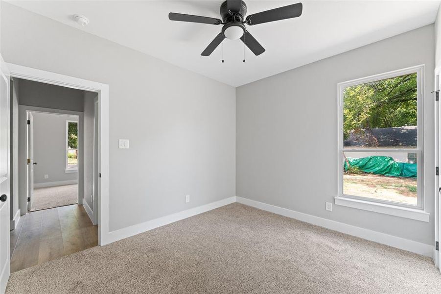 Spare room with light carpet, healthy amount of natural light, and a ceiling fan