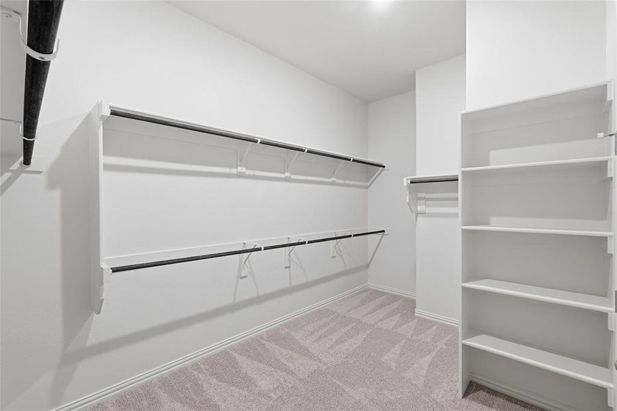 Spacious walk-in closet featuring extensive built-in shelving and hanging rods Spacious walk-in closet featuring extensive built-in shelving and hanging rods