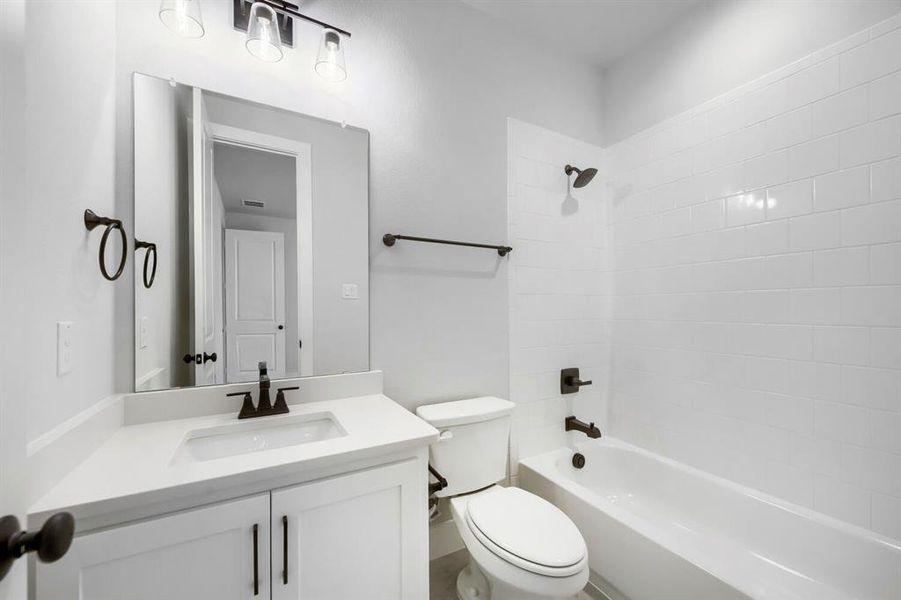 Bathroom featuring a white vanity with an integrated sink, dark bronze fixtures, and a subway tile shower surround