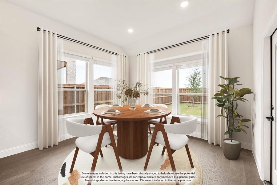 Dining area with round wood table, white chairs, hardwood floors, and large windows with backyard view
