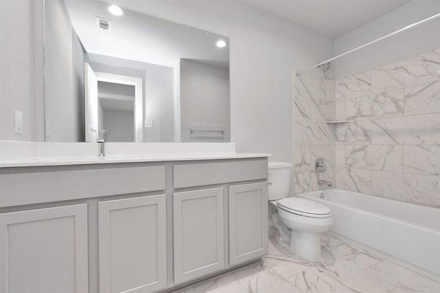 Indulge in refined charm in the secondary bathroom, where the tile flooring harmonizes with a bath/shower combo surrounded by tasteful tile. Light wood cabinets, coupled with a gorgeous countertop, elevate the space, cultivating a truly welcoming atmosphere.