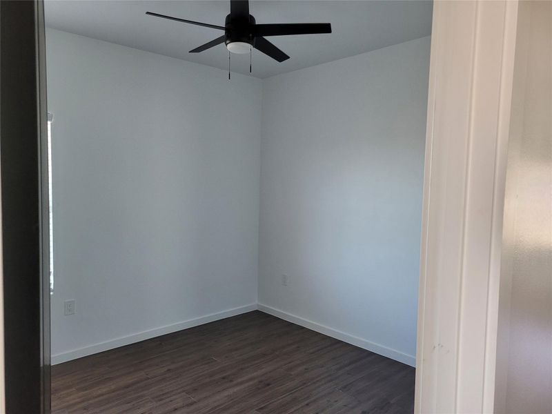 Unfurnished room with dark wood-style floors and a ceiling fan