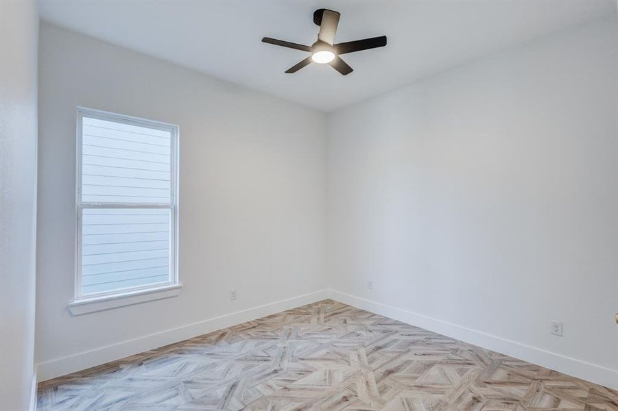 Empty room with ceiling fan and light parquet floors