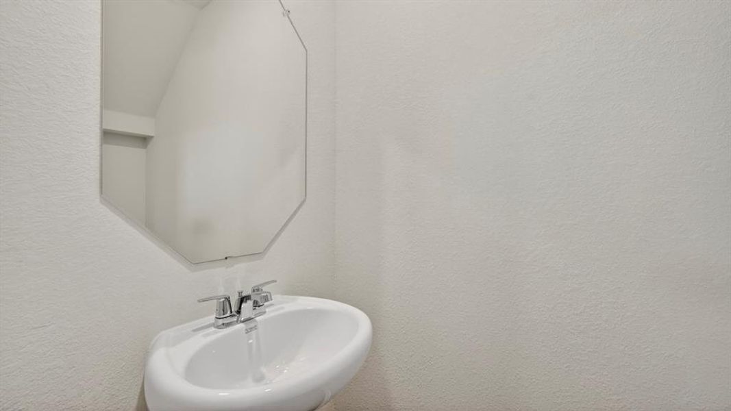 Pedestal sink with chrome fixtures and an octagonal wall mirror